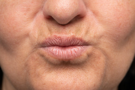Closeup of the mouth of a mature woman with aged lip problem. Wrinkles and signs of aging on the lips of a ladyの写真素材