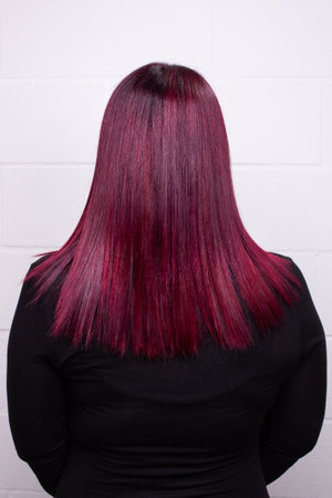 Rear view of the woman with beautiful pink straight long hair wearing black sweater. High-quality photoの写真素材
