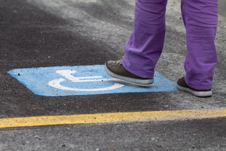 Person stepping on a parking sign reserved for the disabledの写真素材