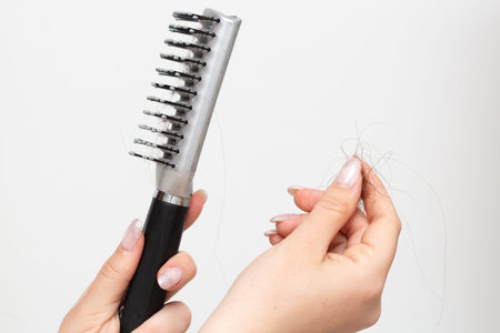 Closeup of female hands with a comb and a lock of fallen hair. Concept of trichotillomania and hair...