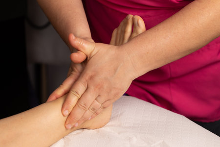 Close-up on the hands of the masseuse performing a relaxing massage on a woman's bare foot. Concept of wellness and reflexologyの写真素材