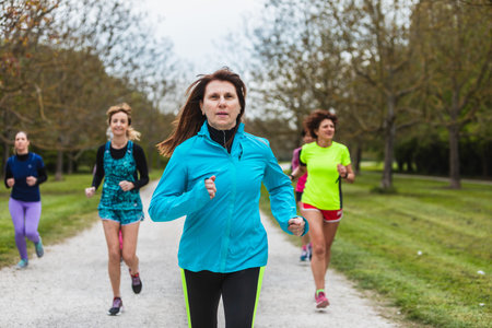An active group of women in various colors of sportswear, from blue to neon green, run together...