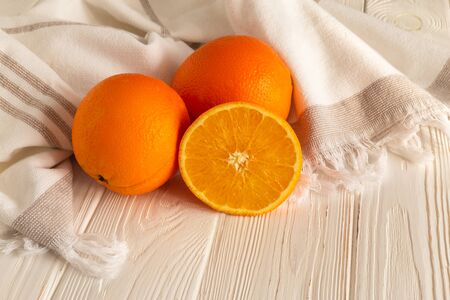Orange on the white wooden kitchen table in linen towel under soft sunlightの写真素材