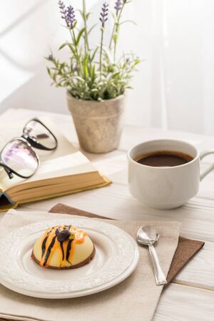 Still life with coffee, cake and a bouquet of lavender on white wooden table. Breakfast in the morning sunの写真素材