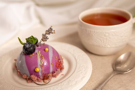 Still life with a cup of tea and sweet cake on white wooden table. Breakfast in the morning sunの写真素材