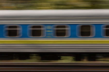 Railroad train high dynamic motion blur, abstract blurred background with green trees, side viewの写真素材