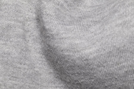This image shows a close-up view of a gray knitted fabric, highlighting the intricate texture and...