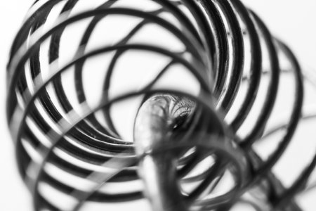 Metal spring coiled, black and white macro shot, soft focus, abstract industrial artの写真素材