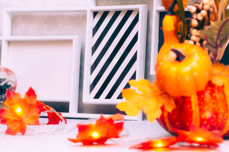 Blank photo frames with pumpkins and a garland of maple leaves on the dresser in room, closeupの写真素材