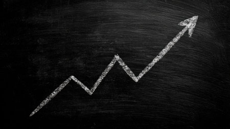 Simple hand-drawn graph on a chalkboard surface with a clear upward trend arrowの素材