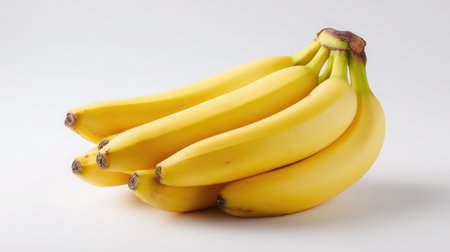 A bunch of bananas with smooth yellow skin placed diagonally on white backdropの素材