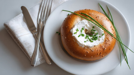 Bagel with cream cheese and chives set neatly on a plate on whiteの素材