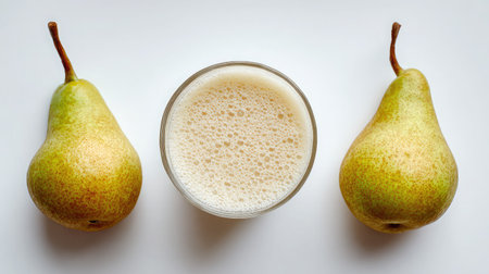 Pear smoothie with subtle color in a clear cup and sliced pears placed symmetrically on whiteの素材