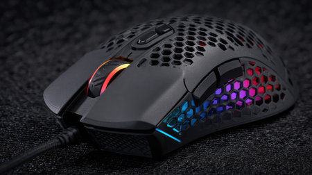 Gaming mouse with RGB lighting effects and extra programmable buttons on a black matの素材