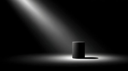 Dramatic spotlight beam casting long shadow behind a cylindrical objectの素材