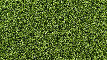 Artificial turf texture in uniform bright green shade creating a sporty backgroundの素材