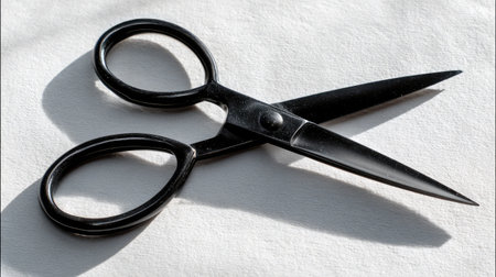 Matte black grooming scissors placed flat on a clean white surface with soft shadowsの素材