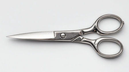 Opened scissors on white background with visible tension screw and polished metalの素材