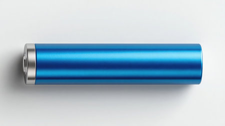 Top-down view of a single AAA battery lying horizontally on a bright white backgroundの素材