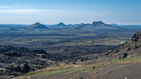 Vast landscape of volcanic rock, ash, and peaks with a quiet volcano in the centerの素材