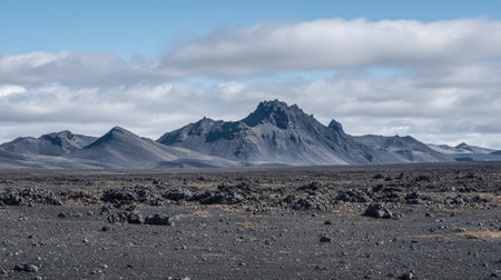 Vast landscape of volcanic rock, ash, and peaks with a quiet volcano in the centerの素材