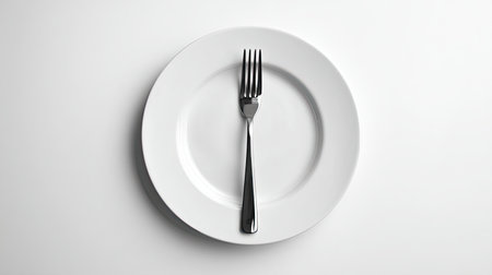 A minimalist composition featuring a white plate and a silver fork centered on a plain background, perfect for culinary themes and food photography.の素材