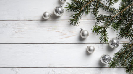 Beautiful arrangement of silver ornaments and pine branches on a white wooden background, creating a charming scene perfect for holiday decorations and events.の素材