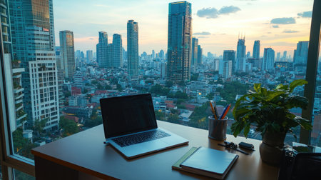 A panoramic view of a city skyline from a high-rise apartment, with a sleek desk setup including a laptop and notepad, symbolizing urban remote workの素材