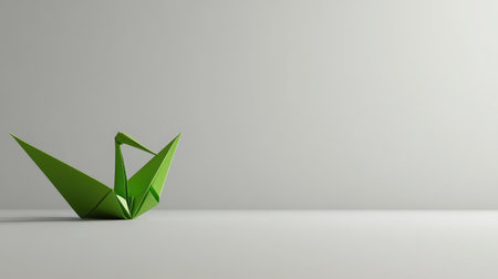 A minimalist design featuring a green origami crane placed on a plain white surface, symbolizing peace and simplicity.の素材