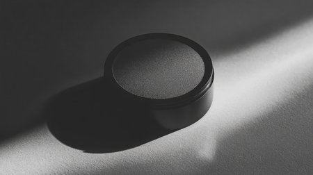 A sleek black container rests on a white surface, casting soft shadows that enhance its minimalist appeal, perfect for modern product showcases or creative branding projects.の素材