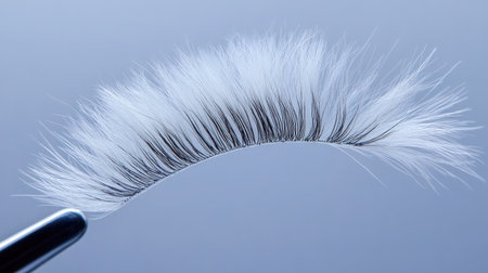 Close-up of a makeup brush featuring soft, fluffy bristles against a light blue background, showcasing the artistry and precision essential for beauty application.の素材
