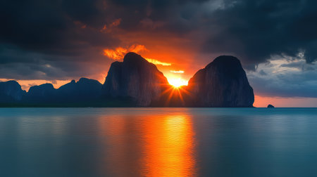 Experience a stunning sunset over calm waters with dramatic mountain silhouettes and vivid colors reflecting across the surface, creating a peaceful atmosphere.の素材