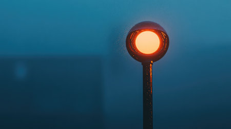 A mesmerizing street light emits a soft orange glow amidst a foggy backdrop, enhancing the mood and atmosphere of tranquility and mystery in the urban setting.の素材