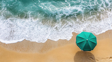 A serene beachscape with a green umbrella highlighting the gentle waves lapping against the golden sand, creating a perfect summer getaway atmosphere filled with relaxation.の素材