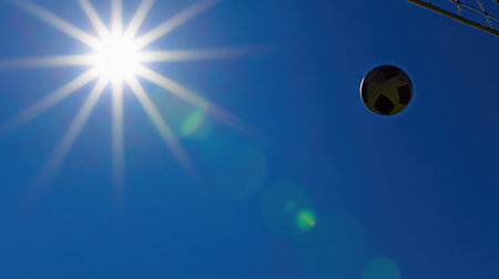 A vibrant scene featuring a soccer ball soaring against a brilliant blue sky and shining sun, symbolizing outdoor activity, sports energy, and the joy of summer games.の素材