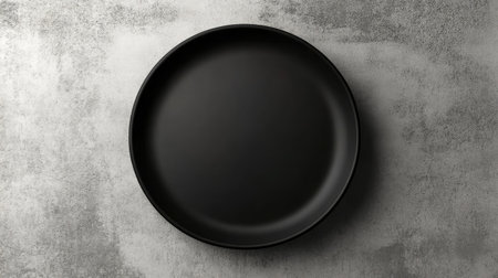 A sleek minimalist black plate on a textured gray background, perfect for showcasing culinary creations in a modern dining or restaurant setting.の素材