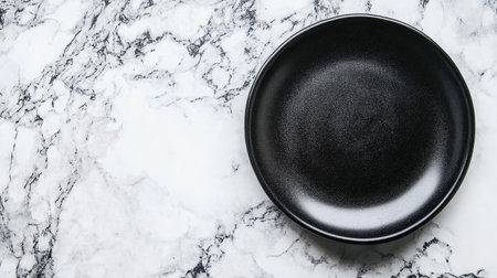 A sleek black plate rests elegantly on a textured white marble surface, ideal for showcasing food and perfect for modern dining aesthetics and culinary presentations.の素材
