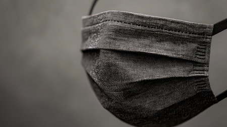 A detailed close-up image of a black cloth face mask, emphasizing its fabric texture and design, suitable for health and fashion themes in various contexts.の素材