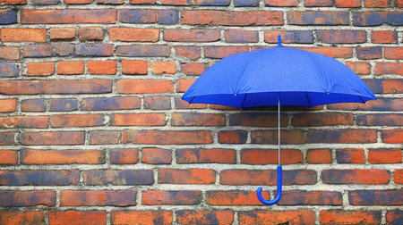A striking blue umbrella hangs gracefully against a weathered red brick wall, adorned with raindrops, capturing a unique blend of charm and urban flair, perfect for creative projects.の素材