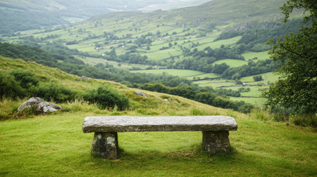 A serene stone bench sits amidst a lush green valley, offering a peaceful spot to relax and enjoy nature's beauty. Ideal for outdoor and travel themes.の素材