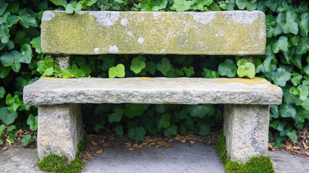 A rustic stone bench covered in moss sits against a backdrop of vibrant green foliage, providing a serene spot for relaxation in nature.の素材