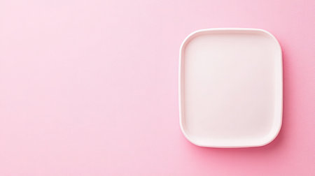This image depicts a minimalist, empty square plate on a soft pink background, perfect for illustrating culinary themes, table settings, or modern design concepts.の素材