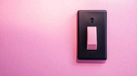 An elegant black light switch mounted on a soft pink wall, showcasing a blend of style and function for any modern home interior. A perfect design element to enhance your space.の素材