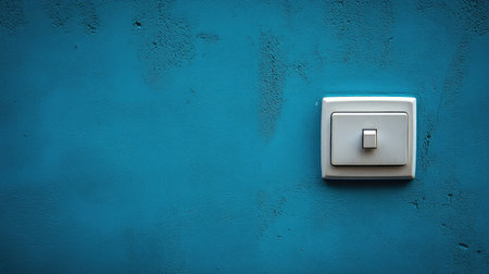 A minimalist light switch mounted on a vibrant turquoise wall showcases modern interior design. The image highlights simplicity and functionality in home decor.の素材