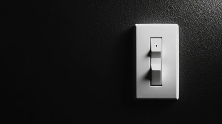 A sleek white light switch mounted on a dark wall, representing a modern aesthetic perfect for contemporary home settings and interior design projects to inspire creativity.の素材