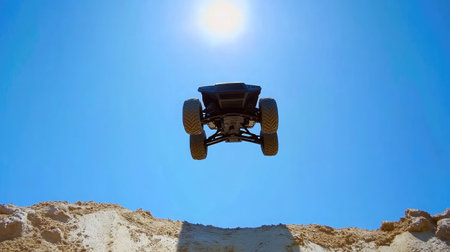 A striking image of an all-terrain vehicle captured mid-air against a vivid blue sky, evoking feelings of excitement and adventure in outdoor sports and exploration.の素材