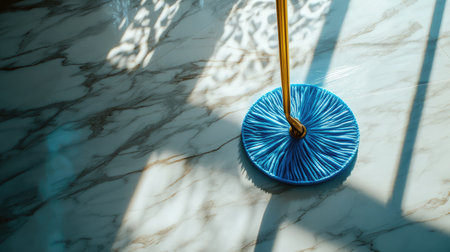 A vibrant blue mop lays on a polished marble floor, beautifully capturing reflections and shadows, ideal for showcasing cleaning tools in a modern home or office setting.の素材