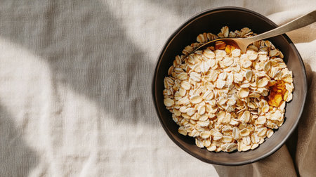 Overflowing cereal bowl with honey-glazed oats, placed on a beige linen tablecloth with spoonの素材
