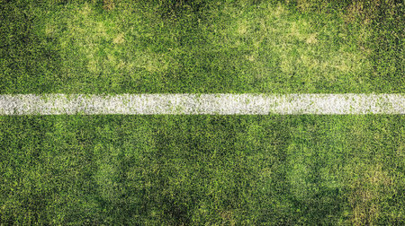 A close-up of a freshly painted white boundary line on a vibrant green football pitch.の素材