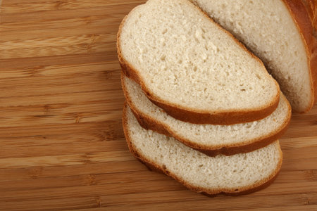 Cut long loaf on kitchen board on white background